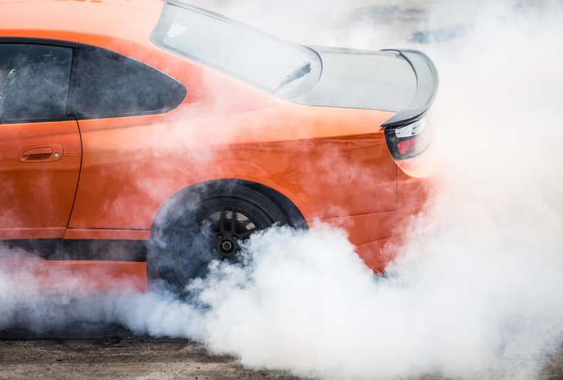 An orange stunt car doing doughnuts on a closed track.