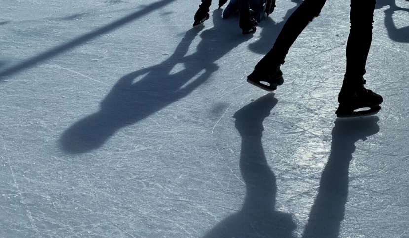 The shadows of ice skaters dancing across the ice at the Federation Square ice r