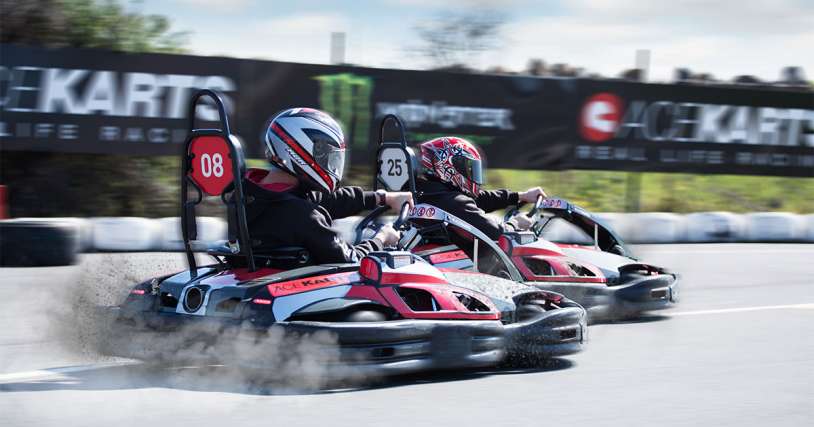 Two go-kart racers in action, leaning into a curve on a track, showcasing their 